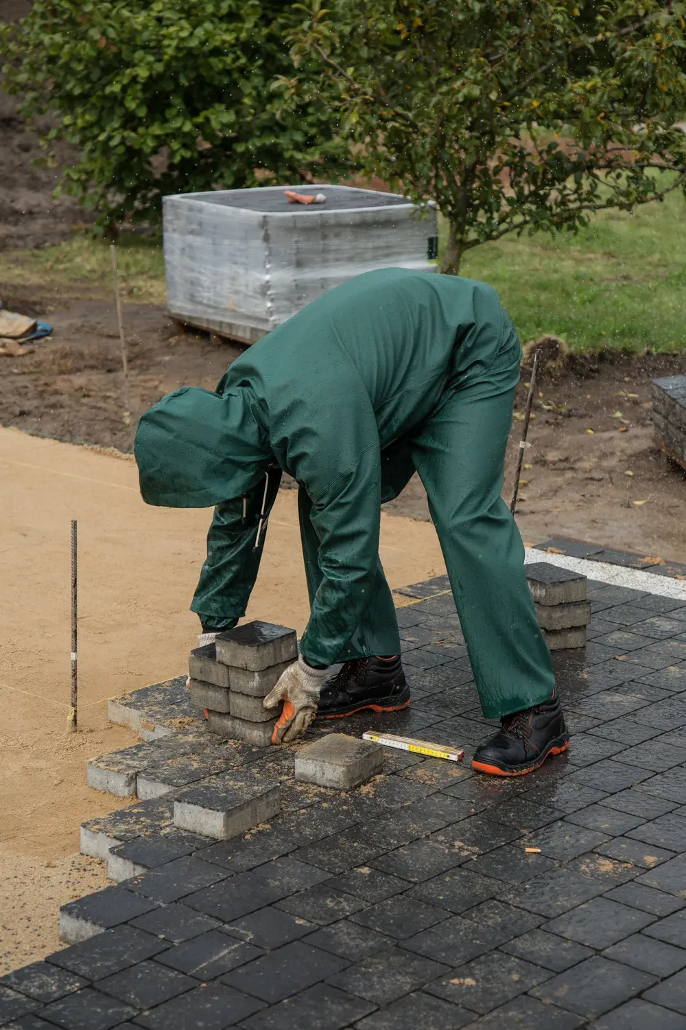 Ouvrier posant des pavés sur une fondation compactée