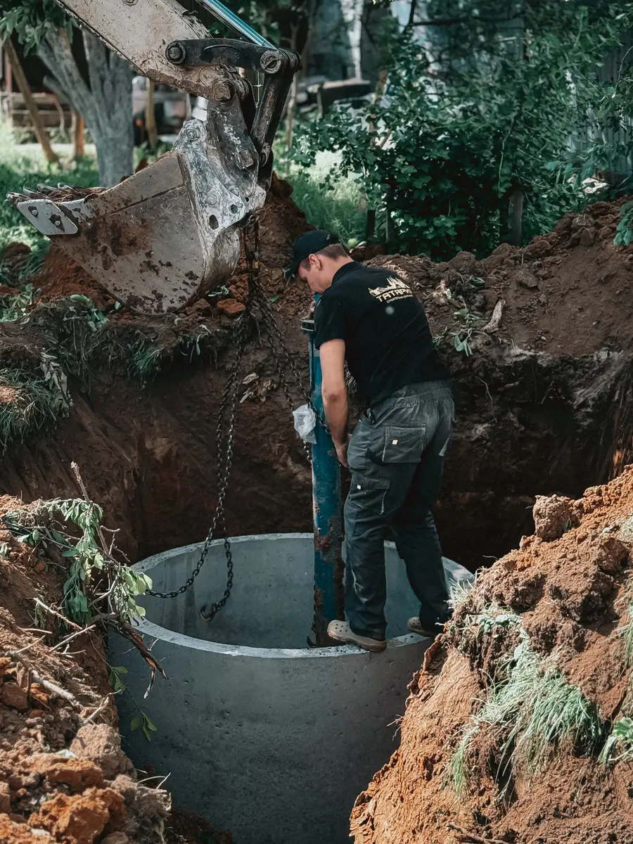 Ouvrier installant un regard de béton dans une excavation